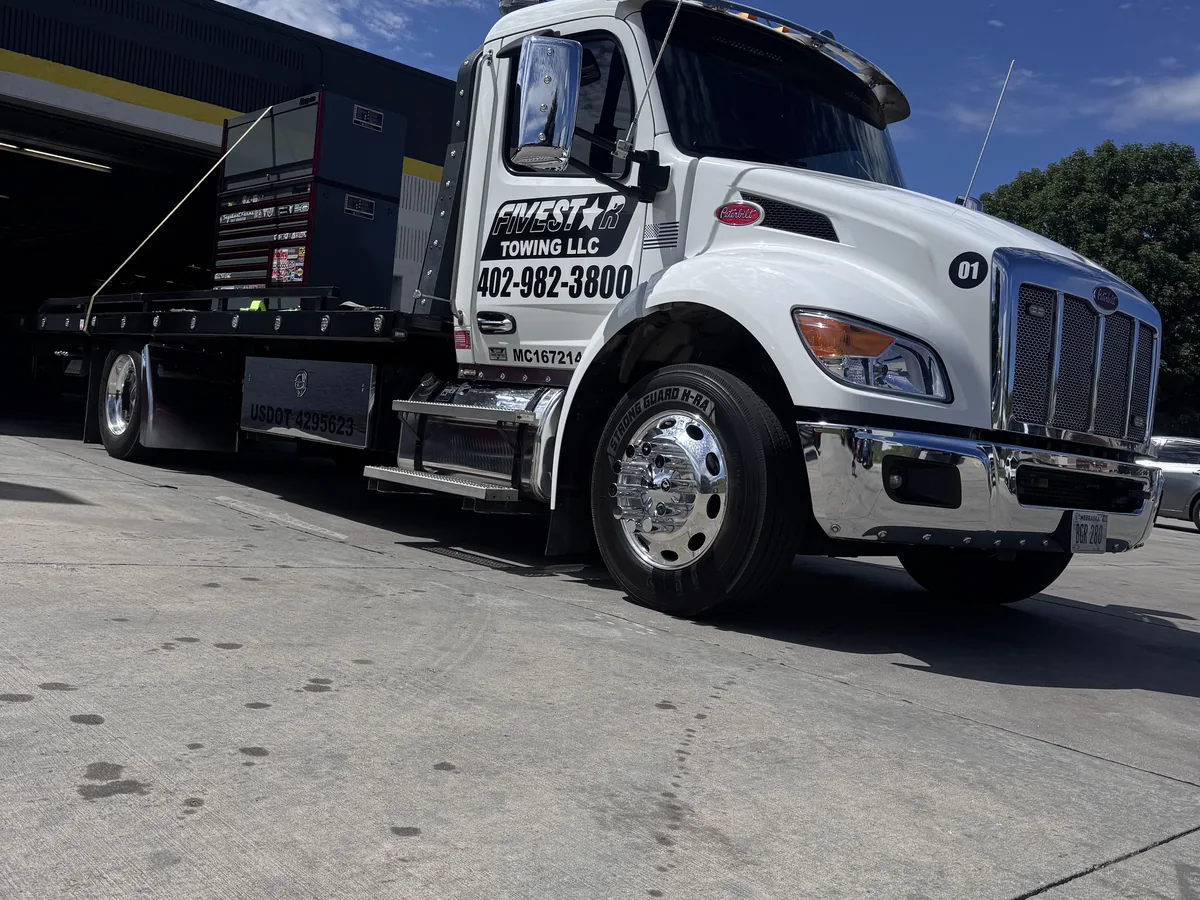 Flatbed tow truck parked at a repair shop bay