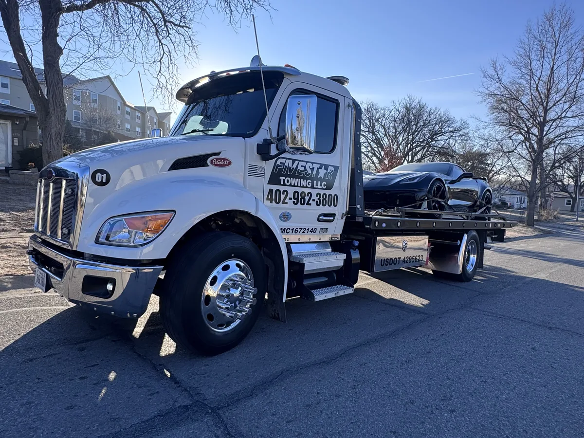 Flatbed tow truck loaded with a black sports car