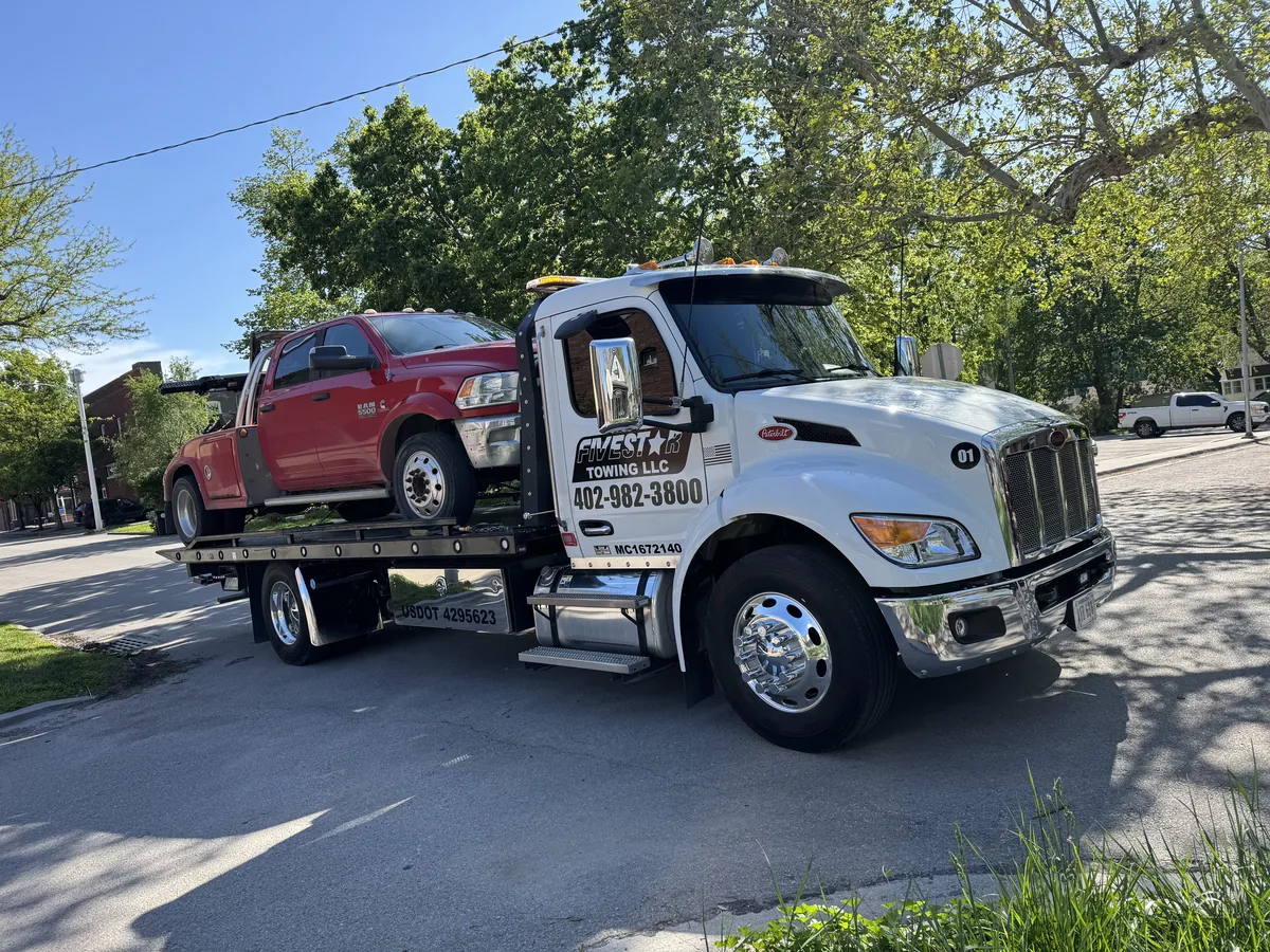 Flatbed tow truck loaded with a red pickup truck