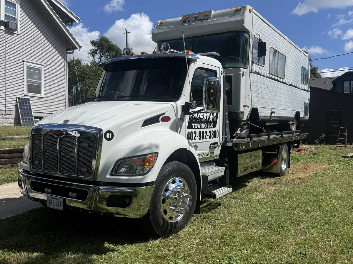 Flatbed tow truck hauling a motorhome RV