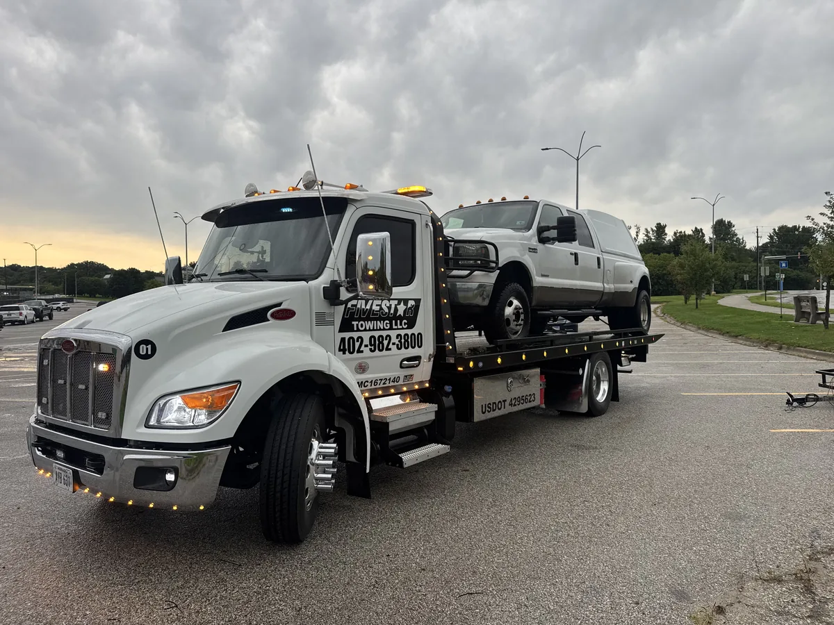 Flatbed tow truck loaded with a silver pickup truck
