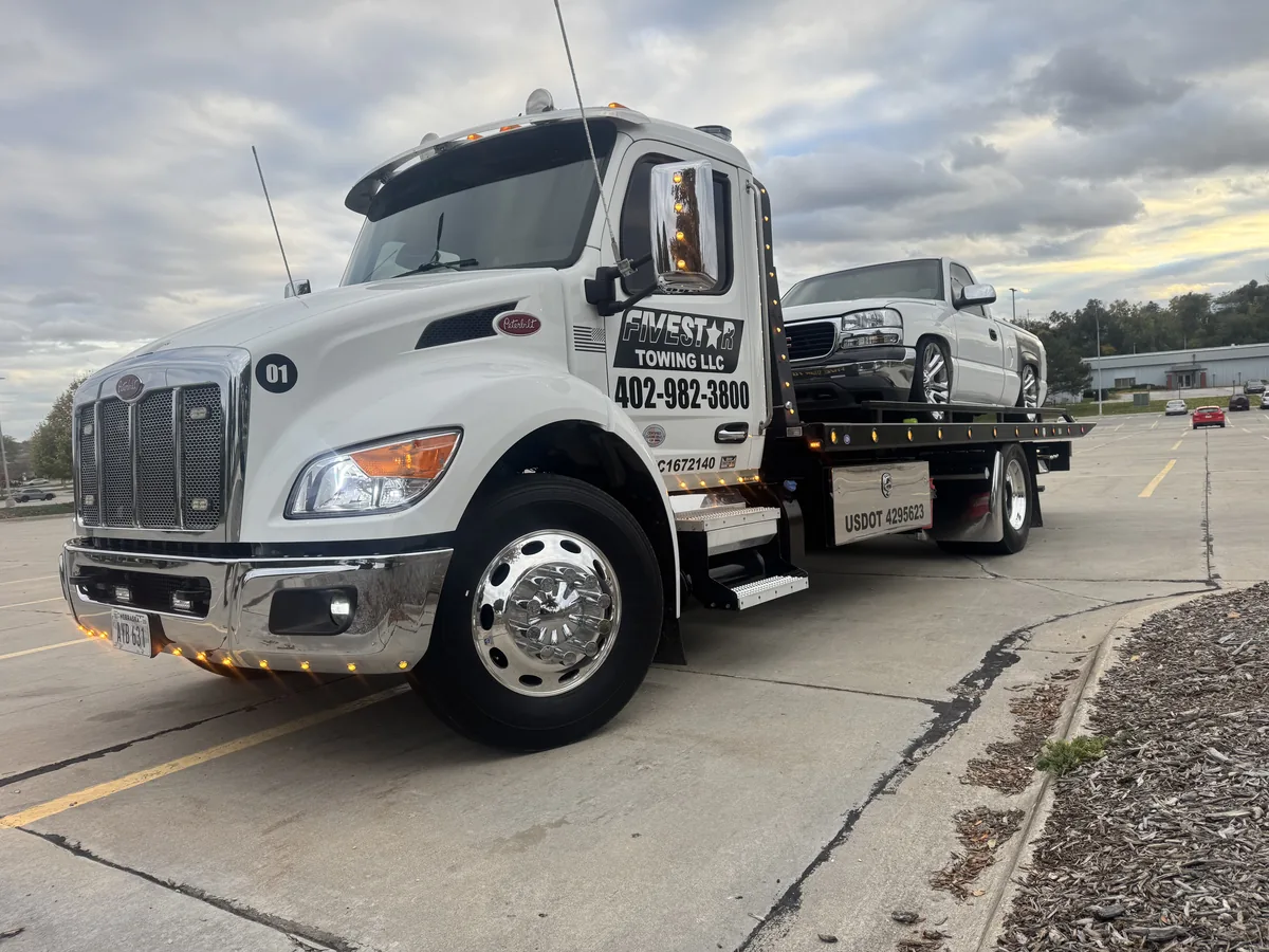 Flatbed tow truck loaded with a silver sedan