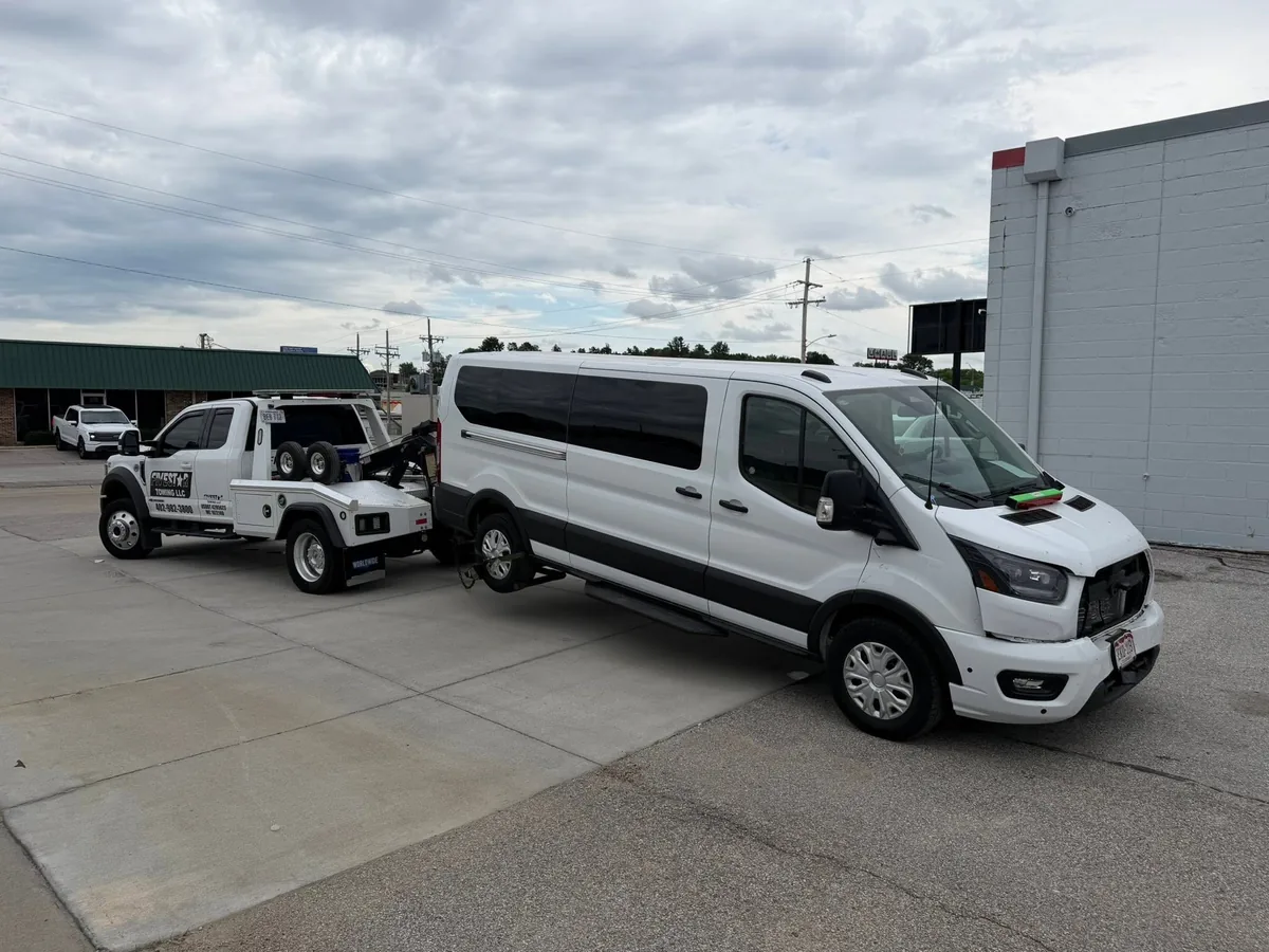 White passenger van loaded on a tow truck deck