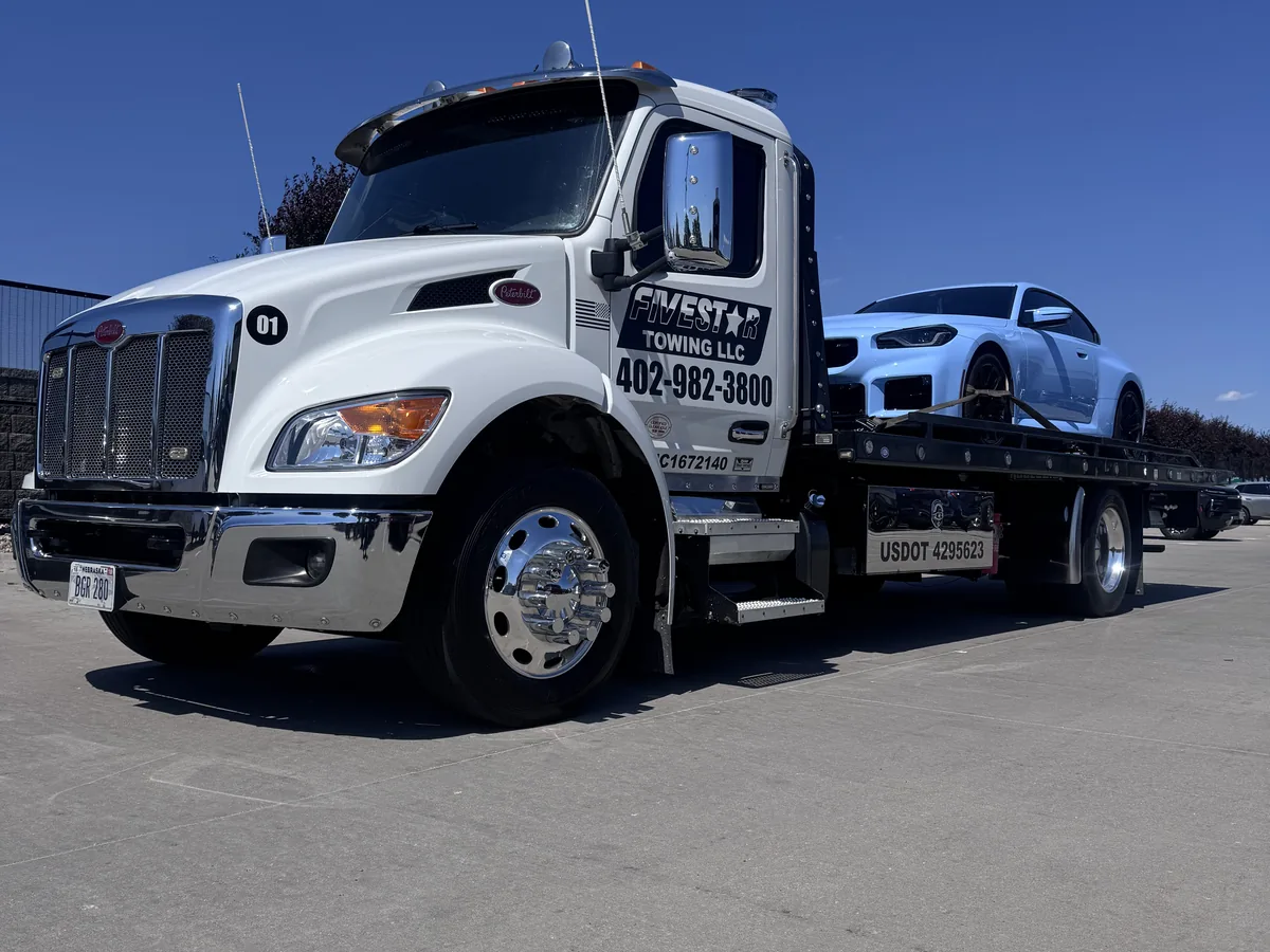 Flatbed tow truck loaded with a white sports car