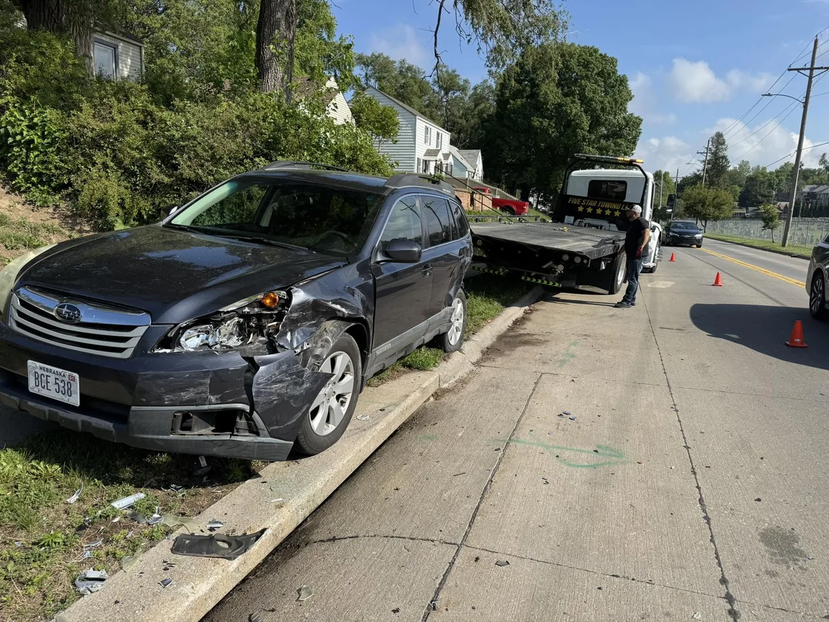 Wrecked black SUV with front end collision damage staged for flatbed loading