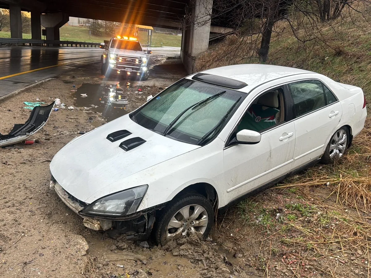 White sedan stuck off the roadway in a ditch before winch recovery